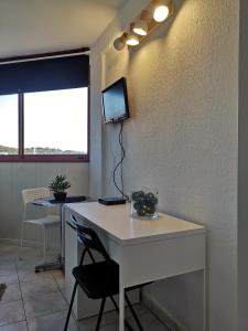 Zimmer mit einem weißen Schreibtisch und einem TV an der Wand in der Unterkunft Studio à 15 minutes des plages in La Valette-du-Var