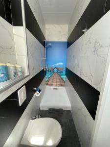 Łazienka z białą toaletą i drewnianą podłogą w obiekcie La Maison Bleue « La Charade » w mieście Thaon-les-Vosges