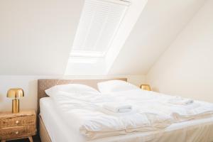 Schlafzimmer mit einem weißen Bett und einem Fenster in der Unterkunft Dünenquartier Apartment 22 in Zingst