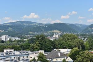 Blick auf eine Stadt mit Bergen im Hintergrund in der Unterkunft SOVEA Hotel - City in Linz