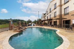 a swimming pool in a yard next to a building at Comfort Suites Marshall in Marshall