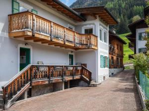 une maison avec balcon en bois dans une rue dans l'établissement Ciasa Lino Sas da le Doudesc, à Pozza di Fassa