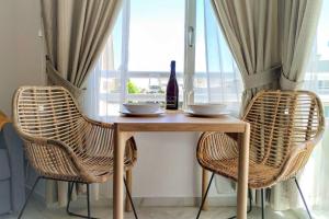 een tafel met 2 stoelen en een fles wijn bij New Doña Carlota Gardens, Sea views, Pool in Torremolinos
