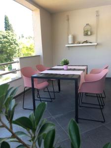 ein Esszimmer mit rosa Stühlen und einem Tisch in der Unterkunft Apartments Nenich Aves in Žman