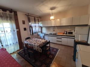 cocina con mesa y cocina con armarios blancos en Family apartment near beach, en Biograd na Moru