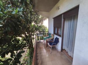 Un balcón con una silla, una mesa y árboles en Family apartment near beach, en Biograd na Moru