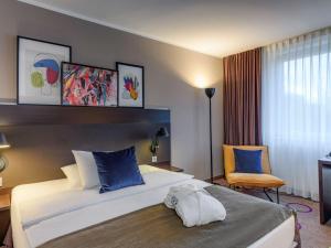 um quarto de hotel com uma cama grande e uma cadeira em Mercure Hotel Hannover Medical Park em Hanôver