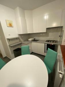 a kitchen with white cabinets and green chairs at Bella apartman Balatonalmádi in Balatonalmádi