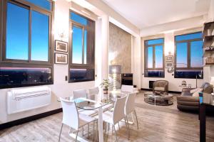 - un salon avec une table en verre et des chaises blanches dans l'établissement Haut Lofts - Toulouse Centre Ramblas, à Toulouse