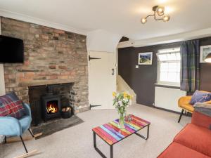 a living room with a fireplace and a couch and a table at Kooky Cottage in Brecon