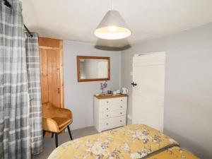 une chambre avec un lit, une commode et un miroir dans l'établissement Kooky Cottage, à Brecon