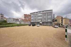 a parking lot with cars parked in front of a building at Hotel VIDA Finisterre Centro in Finisterre