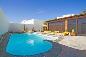 una piscina con sedie gialle e una casa di V PRINCESA vivienda con piscina climatizada y bbq a Puerto del Carmen