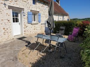 a table and chairs with an umbrella in front of a building at Gîte le Pilon in Verdon