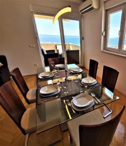 ein Esszimmer mit einem Glastisch und Stühlen in der Unterkunft Apartment Makarska, panoramic sea & mountains view, Čuček in Makarska