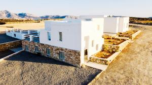 a white building in the desert with mountains in the background at Aeris suites pori semi basement villa in Koufonisia