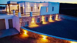 a house with lights on the side of it at night at Aeris suites pori semi basement villa in Koufonisia