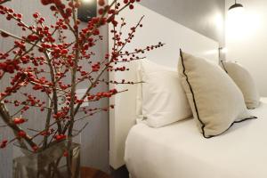 łóżko z białymi poduszkami i drzewo z czerwonymi jagodami w obiekcie Reina Sofia Boutique II w Madrycie