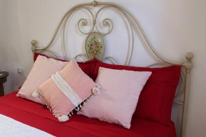 Una cama con almohadas rojas y rosas. en Emy's Country House, en Castellammare di Stabia