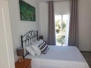 1 dormitorio con 1 cama con sábanas blancas y ventana en Habitación Aponiente, en Conil de la Frontera