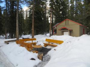 una cabaña en la nieve con bancos delante en HI Mosquito Creek - Hostel, en Lago Louise