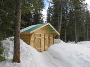 un hangar en bois avec un toit bleu dans la neige dans l'établissement HI Mosquito Creek - Hostel, à Lake Louise