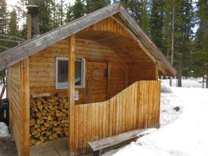 a log cabin with a door and a pile of logs at HI Mosquito Creek - Wilderness Hostel in Lake Louise +16 photos