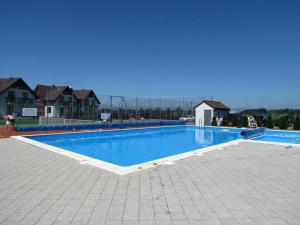 a large blue swimming pool with houses in the background at Apartament Korab in Żarnowska