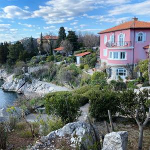 una casa rosa en una colina junto a un río en Apartments Villa Dora, en Kraljevica