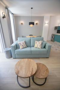 ein Wohnzimmer mit einem blauen Sofa und 2 Tischen in der Unterkunft Apartamentos Líbere Valencia Abastos in Valencia