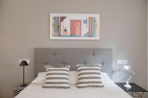ein Bett mit zwei Kissen und einem Bild darüber in der Unterkunft Apartamentos Líbere Valencia Abastos in Valencia