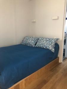 ein Bett mit blauem Bettlaken und zwei Kissen darauf in der Unterkunft Le Studio Goëland in Trouville-sur-Mer