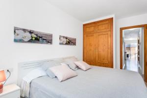 a white bedroom with a bed with two pink pillows at APARTAMENTO PLAYA SAN JUAN in Guía de Isora