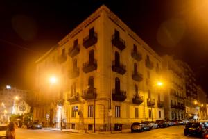 duży budynek z samochodami zaparkowanymi przed nim w nocy w obiekcie Hotel Tonic w mieście Palermo
