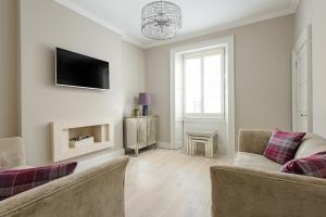 a living room with a couch and a tv on the wall at The Rose Street Apartment in Edinburgh