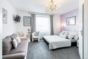 a bedroom with a bed and a couch and a chandelier at A.V.E. Pension Kliská in Prague
