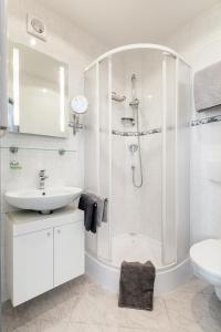 a white bathroom with a shower and a sink at A.V.E. Pension Kliská in Prague