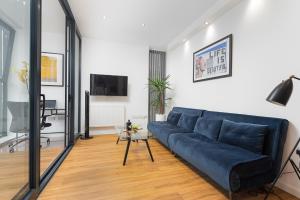 a living room with a blue couch and a table at Modern Kingston Home close to Hampton Court Palace by UndertheDoormat in London