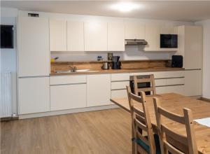 a kitchen with white cabinets and a wooden table at Brandtnerhof Betriebe in Waidring