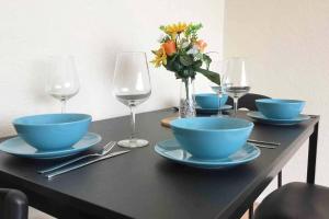a table with blue bowls and glasses of wine at Serene Apt in the Heart of Stretford in Manchester