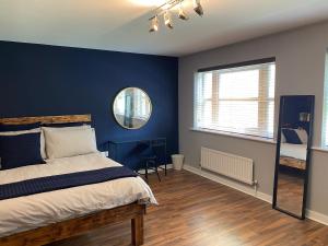a bedroom with blue walls and a bed and a mirror at Riverside Townhouse, Only 20 Minutes from Brighton and Worthing in Shoreham-by-Sea