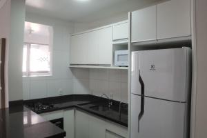a kitchen with white cabinets and a refrigerator at Excelente apto 3 quartos em Bombas, 100 metros do mar e 2 vagas de garagem in Bombinhas