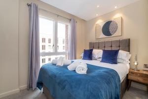 een slaapkamer met een groot bed met blauwe lakens en een raam bij Hudson Quarter Luxury Apartments in York