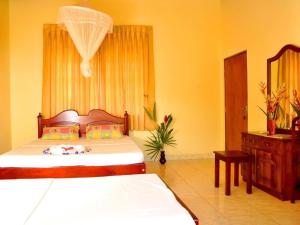 a bedroom with a bed and a dresser and a mirror at Sakura Villa Bentota in Bentota