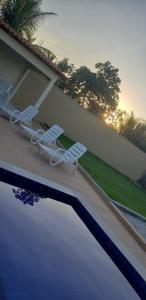 duas cadeiras brancas sentadas ao lado de uma piscina em Dunas Residence casa 04- Lençois Maranhense em Santo Amaro