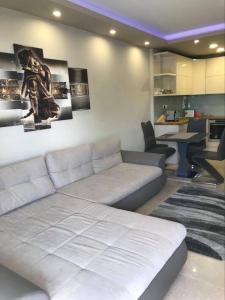 a living room with a white couch and a kitchen at Oasis Residence in Hajdúszoboszló