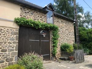 a building with a garage with a basketball hoop on it at Chambre à la campagne in Québriac