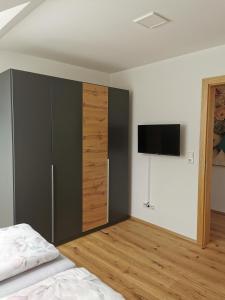 a bedroom with a large wardrobe and a television at Living Apartment_2 in Hittisau