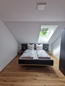 ein Schlafzimmer mit einem Bett im Dachgeschoss mit einem Fenster in der Unterkunft Living Apartment_2 in Hittisau