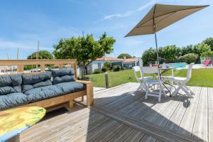 a wooden deck with a couch and a table with an umbrella at Cosy Corner in Saint-Xandre